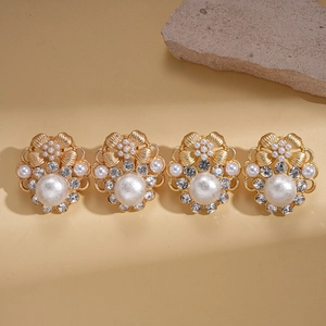 Vintage gold flower earrings set with faux pearls and crystals on a warm textured background
