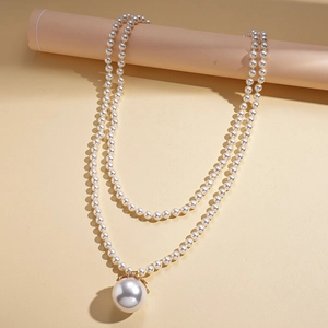 Detail of elegant double-layer long pearl necklace with large pendant on a beige stand