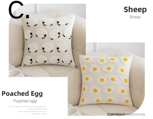 Detail of embroidered sheep and poached egg patterns on soft beige boucle pillow covers