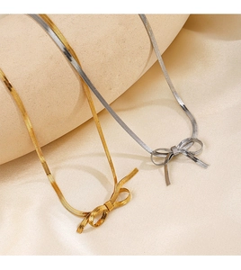 Macro detail of gold and silver bow pendants on snake chain necklaces with metallic texture