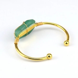 Macro detail of handmade gold wire-wrapped bracelet with natural green raw stone crystal