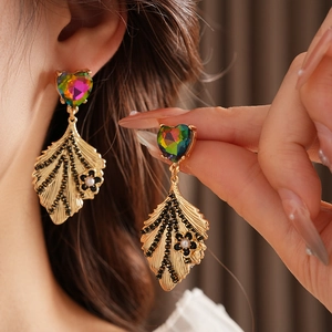 Detail of vintage gold heart earrings with leaf pendant and pearl dangle for women