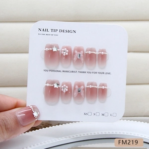 Pink ombre press-on nails with pearls, stars, and bows on a white display card