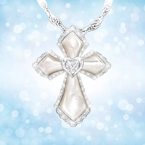 Macro view of silver cross pendant with white mother-of-pearl and heart-shaped diamond