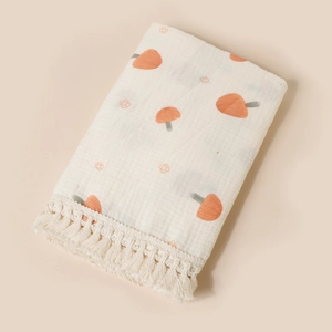 Detail of baby cotton gauze blanket featuring mushroom print and delicate fringe trim