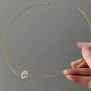 Collier ras du cou doré minimaliste avec zircon ovale et pointes sur fond gris foncé
