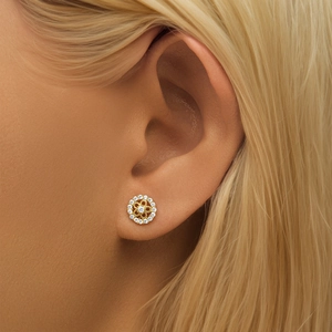 Close-up of golden diamond flower earrings with white zircon on woman's earlobe