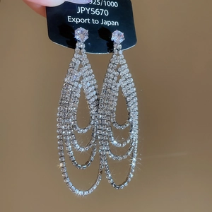 Détail de boucles d'oreilles pendantes en argent 925 avec strass blancs et glands longs