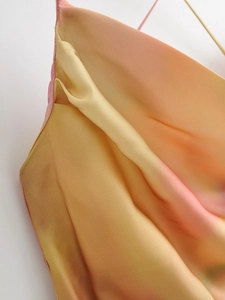 Detailed view of tie-dye satin fabric showing smooth texture and drapes in orange pink gradient