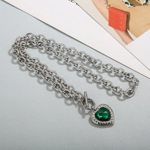 Macro shot of silver OT toggle chain necklace with green heart-shaped emerald gemstone
