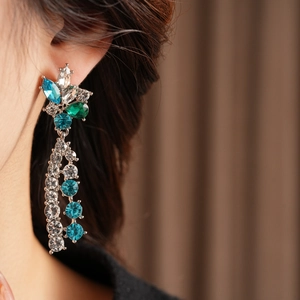 Close-up of vintage flower tassel earrings with blue and clear rhinestones on model