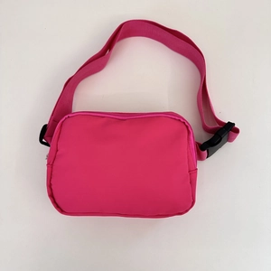 Detail of adjustable strap and buckle on pink nylon waist bag with focus on hardware