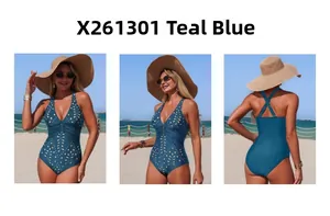 Three-way view of a teal blue one-piece swimsuit with laser-cut floral details on a beach