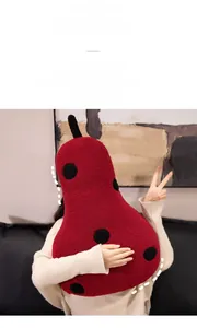 Macro detail of red pear plush pillow with black dots and soft grainy texture