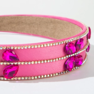 Macro detail of pink satin headband featuring rows of rhinestones and teardrop gems