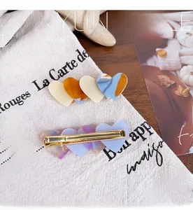 Close-up of heart acetate hair clips with marble texture and gold metal grip