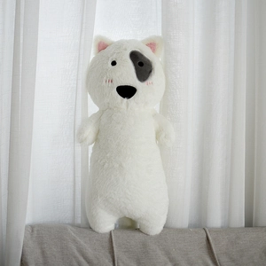Close-up of white plush dog toy with black eye patch and soft pink embroidery detail