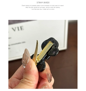 Detailed view of black marble acetate butterfly hair clip with gold metal duckbill clip