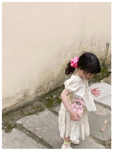 Detailed close-up of a pink pleated mini bucket bag with pearl handle for young girls
