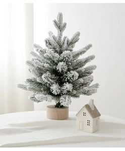 Close-up of a mini flocked Christmas tree with snow effect and a rustic wooden base