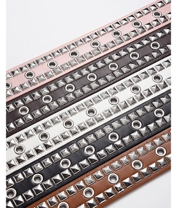 Detailed macro view showing five colors of punk rivet belts with silver metal studs