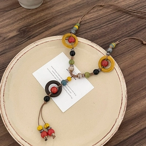 Close-up of bohemian handmade necklace with colorful wooden beads and woven tassel detail