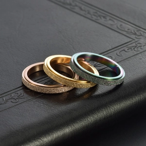 Golden and rainbow minimalist frosted spinner rings set on black textured leather surface