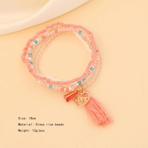 Macro shot of layered pink and white bead bracelet with Love heart charm and tassel