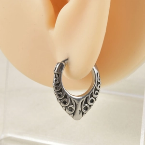 Detailed close-up of antique silver earring with intricate gothic floral engravings