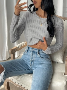 Close-up of grey ribbed knit long-sleeve crop top texture with high-waisted denim jeans