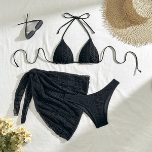 Detail of black three-piece bikini set with textured fabric and mesh sarong cover-up