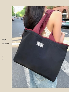 Detail of the durable black nylon shopping bag with wine red shoulder straps on a model