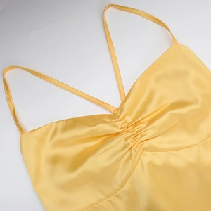 Detail of yellow satin dress featuring pleated bust design and silky smooth texture
