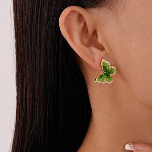 Close-up of green crystal butterfly earring with gold plating on female model