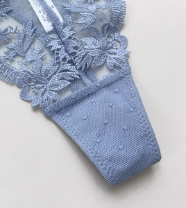 Detail view of light blue floral embroidery lace and mesh fabric with cotton lining