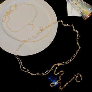 Detail shot of a minimalist gold body chain featuring delicate pearls and zircon beads