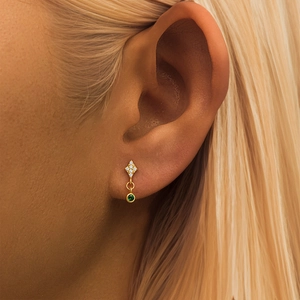 Detail of s925 silver drop earring with white zircon and round green emerald gemstone