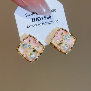 Detailed macro view of vintage gold stud earrings with pink mother-of-pearl and floral enamel