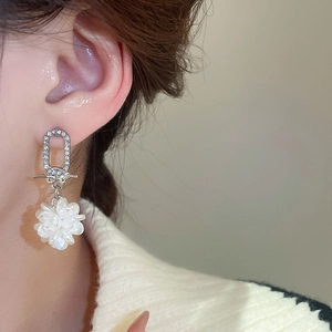 Detailaufnahme eines silbernen Blumenohrrings mit Diamanten und Harzblütenblatt am Ohr