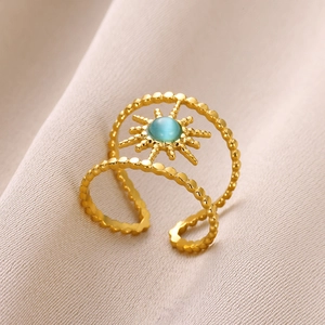 Detail of gold sunburst ring featuring a blue cat-eye stone on beige satin fabric