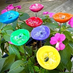 Colorful flower shaped ceramic bird feeders on metal stakes in a natural garden setting