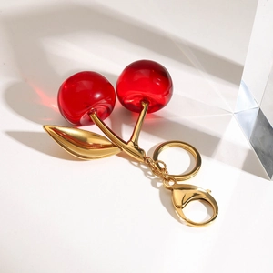 Detailansicht eines roten Kirsch-Schlüsselanhängers mit goldenen Blättern und Karabinerverschluss