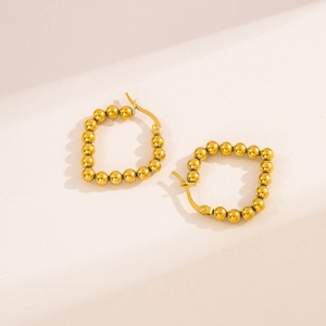 Minimalist gold stainless steel ball bead earrings on a textured beige background