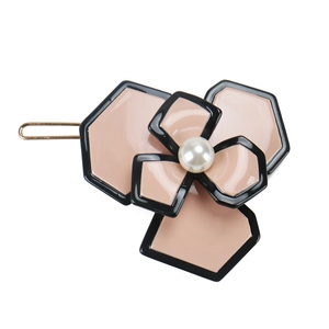 Macro detail of acetate camellia hair clip with black edges and a faux pearl center