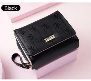 Close-up of black leather wallet with floral embroidery and gold metal logo plaque