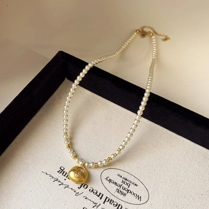 Detail of pearl necklace with gold longevity lock pendant on jewelry display tray