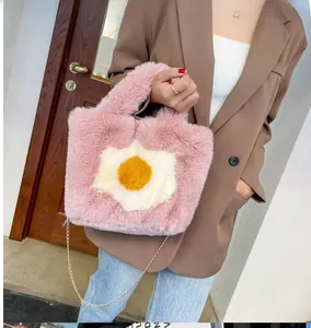 Detail of pink plush tote bag with poached egg appliqué and elegant gold chain strap