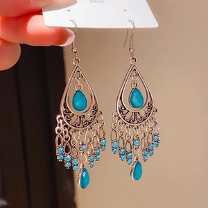 Detailed view of bohemian teardrop earrings with turquoise stones and silver chain tassels