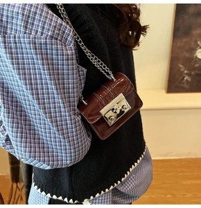 Detail shot of mini burgundy patent leather crossbody bag with silver chain strap