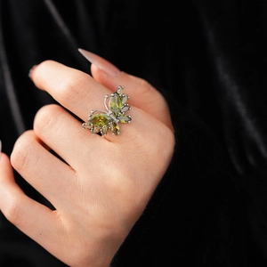 Gros plan détaillé de la bague papillon avec zircons vert olive sur la main d'un mannequin